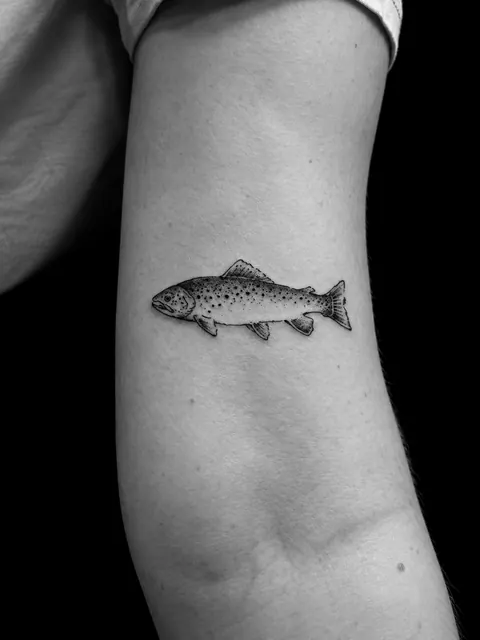 Tatuaje microrrealista de una trucha en la parte trasera del brazo