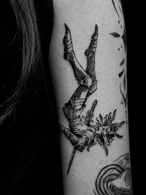 Tatuaje de estilo grabado con una figura que cae y un pájaro en un brazo