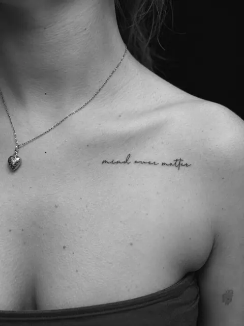 Tatuaje de letra cursiva con la frase «mind over matter» a lo largo de la clavícula