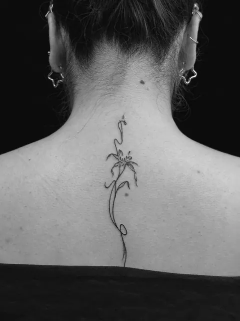 Tatuaje fine line de una flor a lo largo de la columna