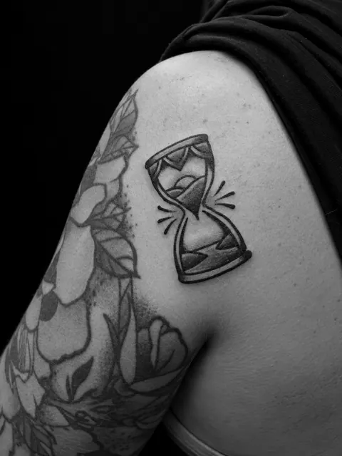 Tatuaje tradicional de un reloj de arena en un hombro
