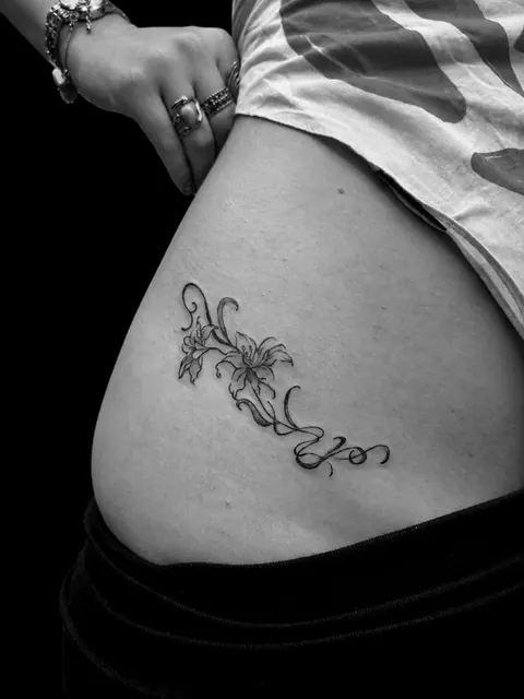 Tatuaje fine line de una enredadera de lirios en una cadera
