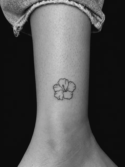 Pequeño tatuaje fine line de un hibisco sobre el tobillo