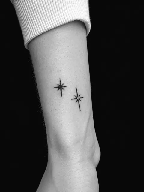 Dos pequeñas estrellas fine line en un antebrazo