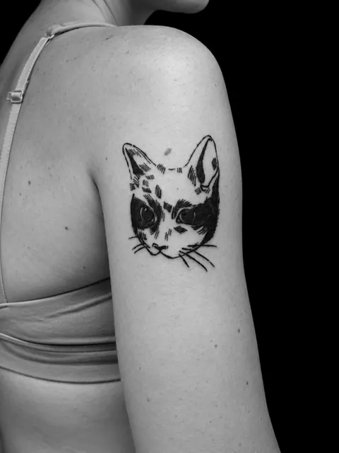 Tatuaje blackwork de la cara de un gato en la parte superior del brazo