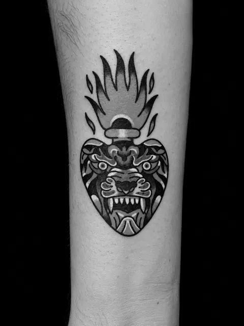 Tatuaje tradicional de una cabeza de león en llamas con forma de corazón en una espinilla