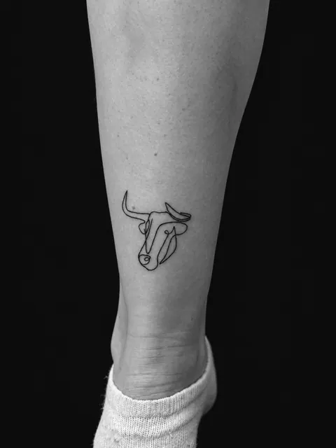 Tatuaje de un toro de una sola línea, al estilo de Picasso, en un gemelo