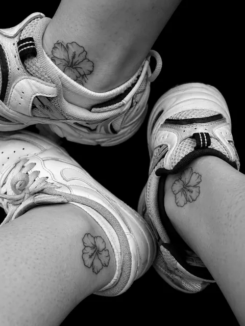 Tres tatuajes iguales de línea fina de una flor de hibisco en tobillos