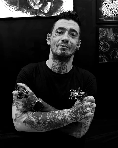 Lorenzo en el estudio, con los brazos cruzados y una máquina de tatuar en cada mano